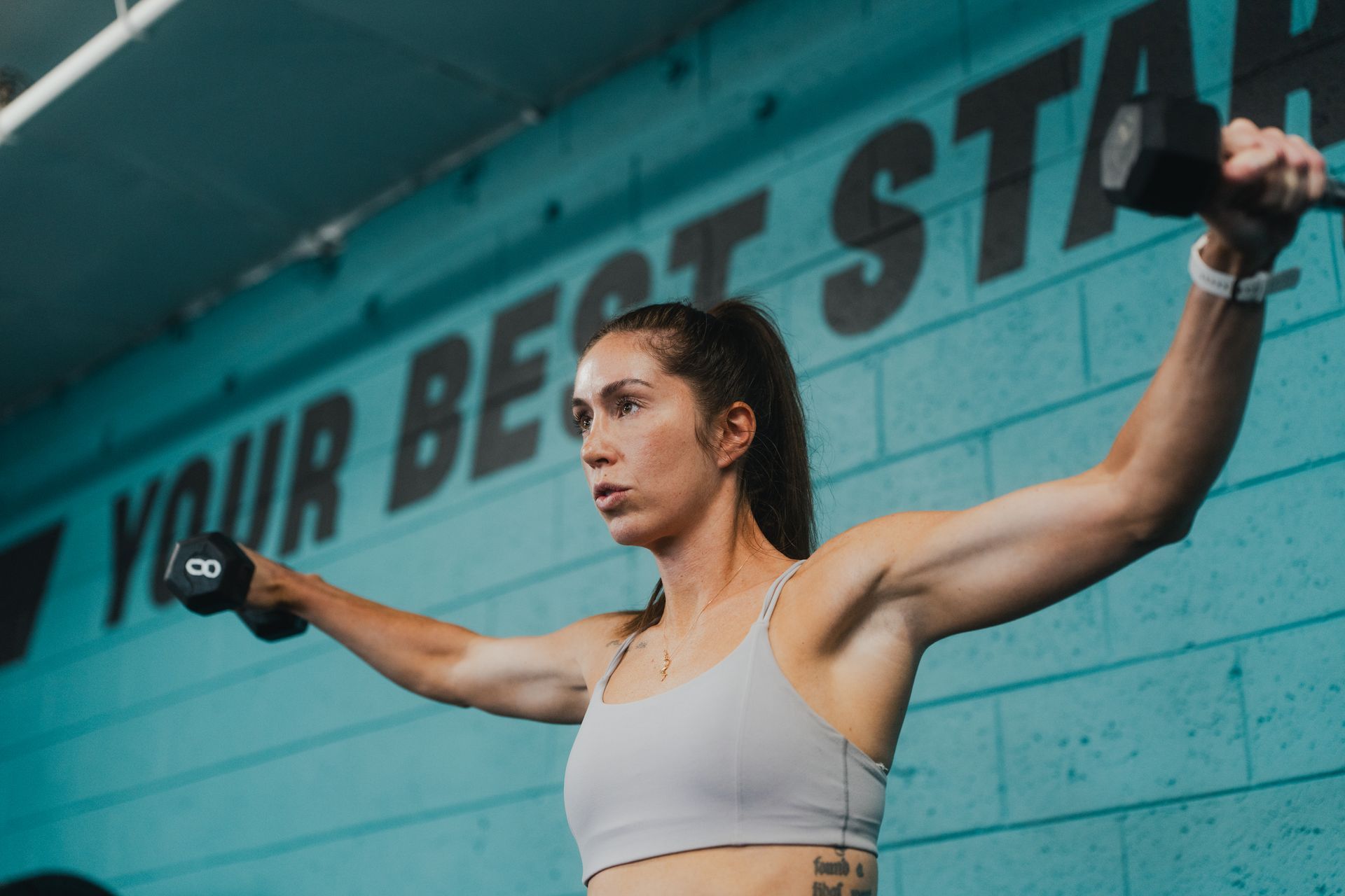 A man and a woman are doing pull ups in a gym.