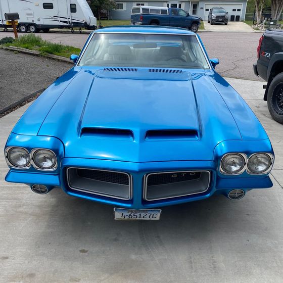Bright blue classic Pontiac Firebird parked in a driveway, front view.