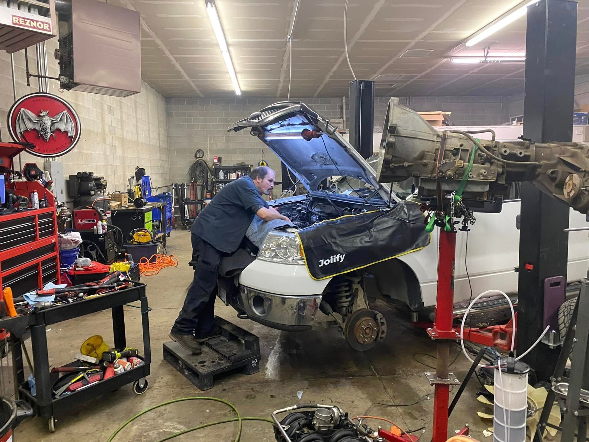Mechanic working on a car with the hood open in an auto repair shop