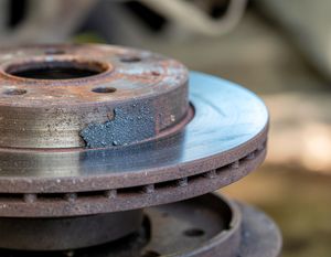 Rusty car brake rotor with a shiny worn friction surface, close-up view