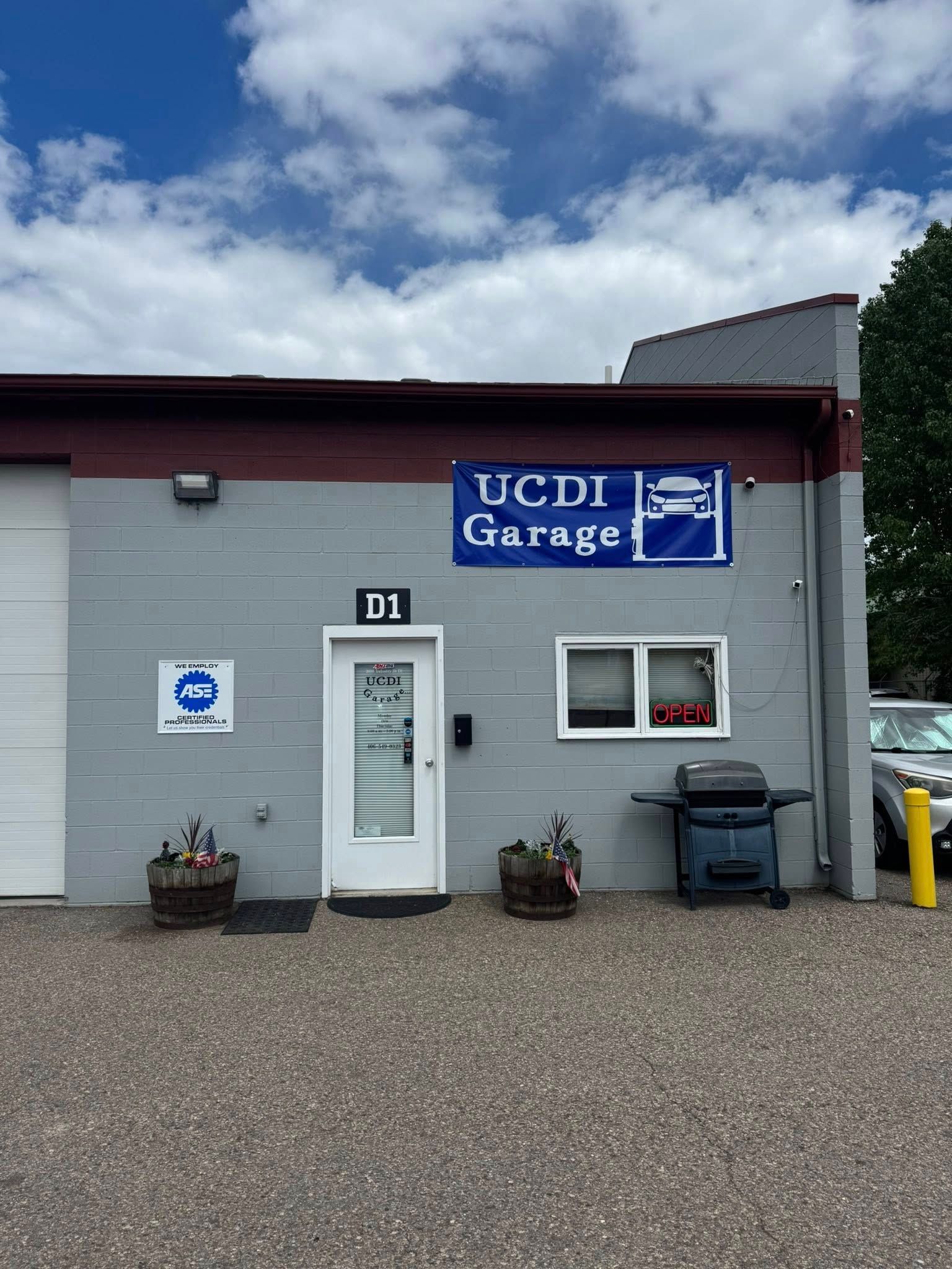 UCiD Garage building with gray exterior, white door, blue sign, and parked bins outside