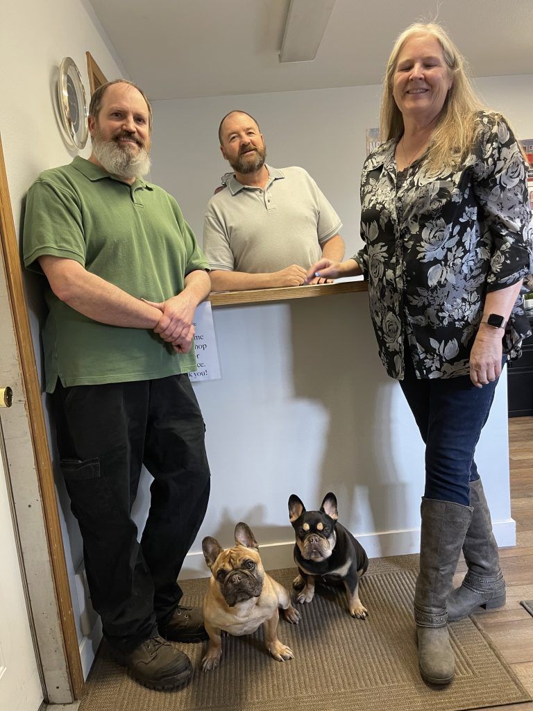 Three people and two dogs standing in a hallway by a counter