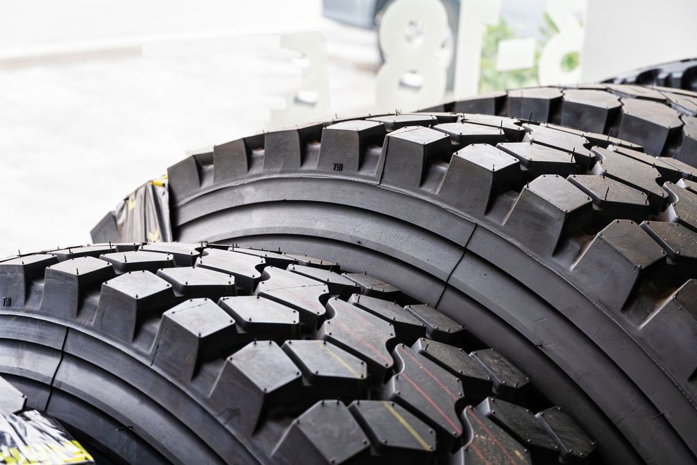 Close-up of two black off-road tires with deep tread, stacked side by side indoors