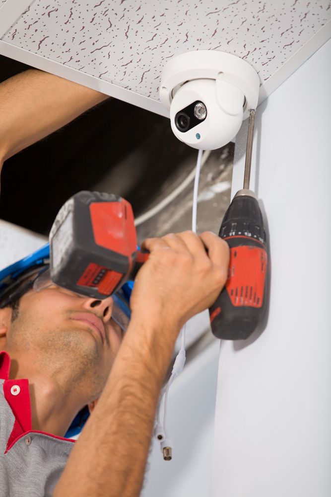 Person Installing Security Camera on Ceiling With Drill — Powered By JBES In Sandgate, NSW