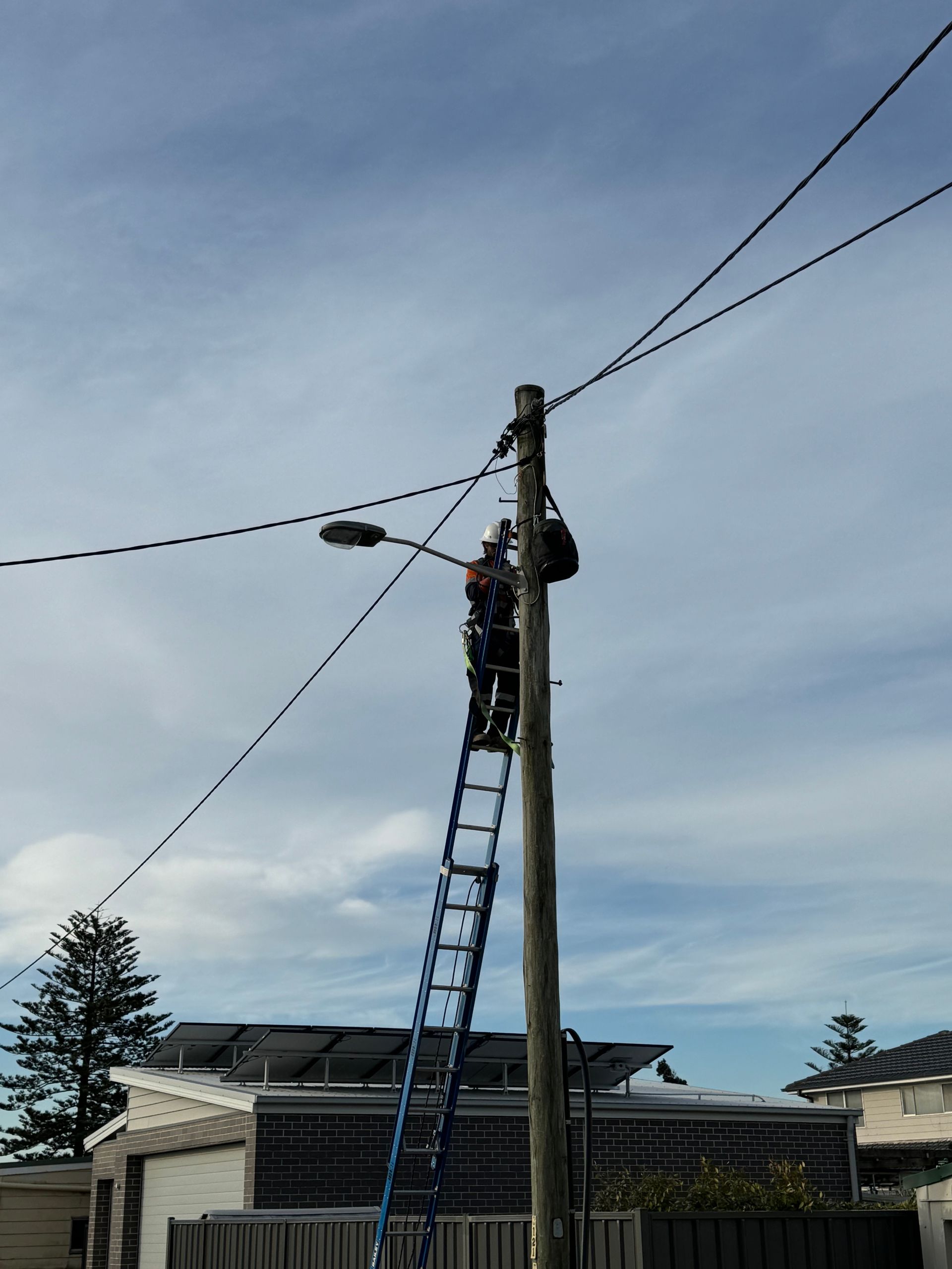 Utility worker on a ladder, working on a utility pole with power lines — Powered By JBES In Port Stephens, NSW