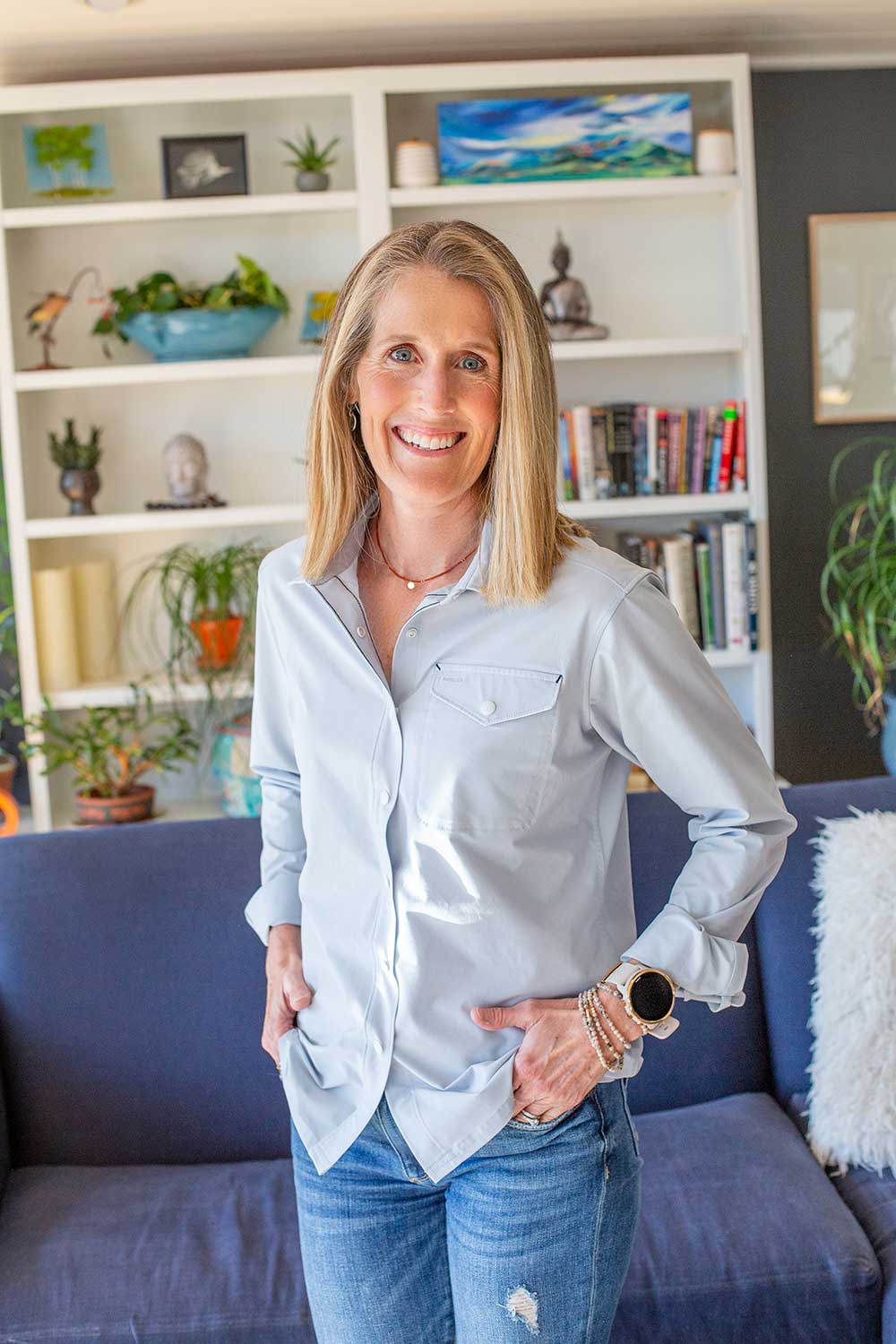 A woman is standing in a living room with her hands on her hips.