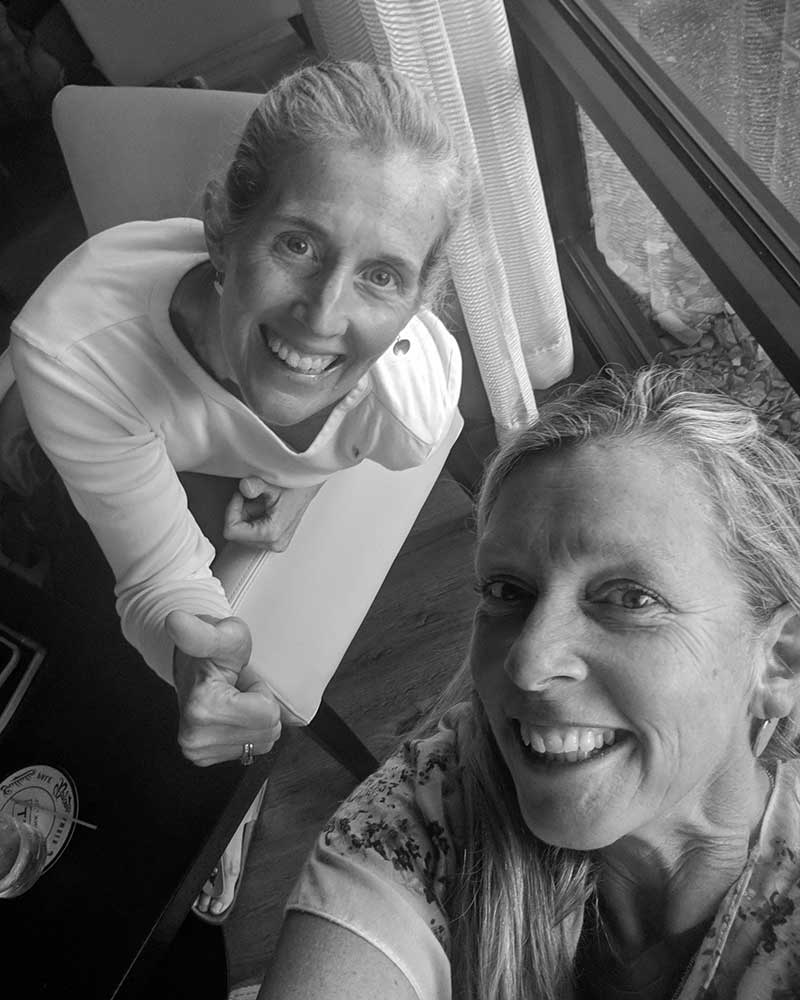 Two women are shaking hands and smiling in a black and white photo.