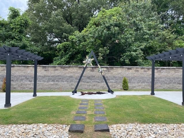 Garden with a wooden A-frame swing, stepping stones, and pergolas along a stone wall