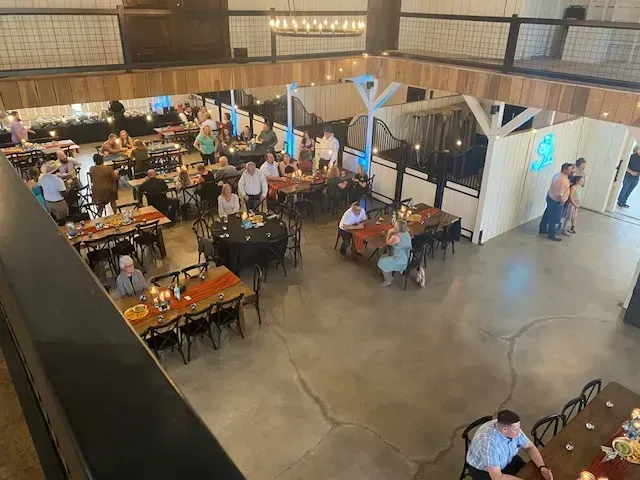 Large indoor dining hall with many people seated at tables and a bar area in the background