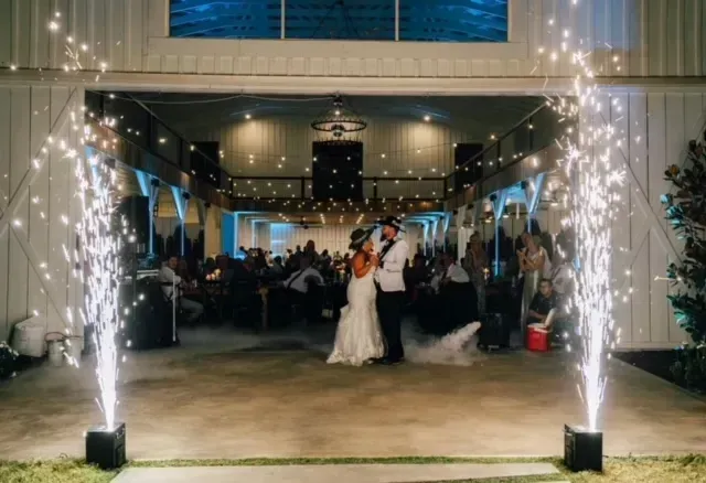 Bride and groom dance under sparkling fountains at a decorated indoor wedding reception