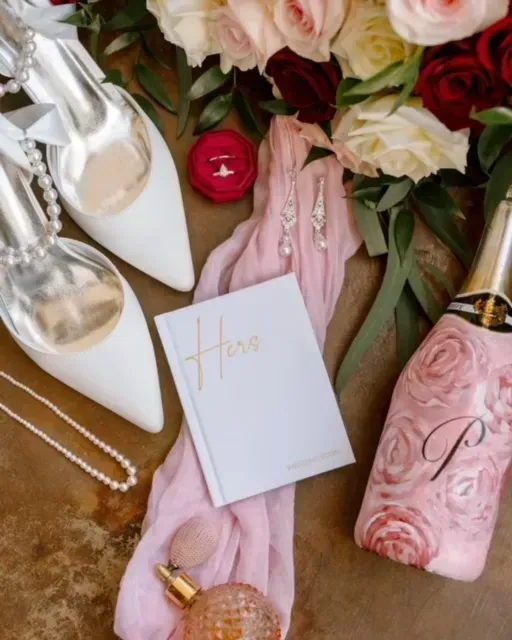 Pink perfume bottle and matching accessories arranged with flowers and a card on a wooden surface