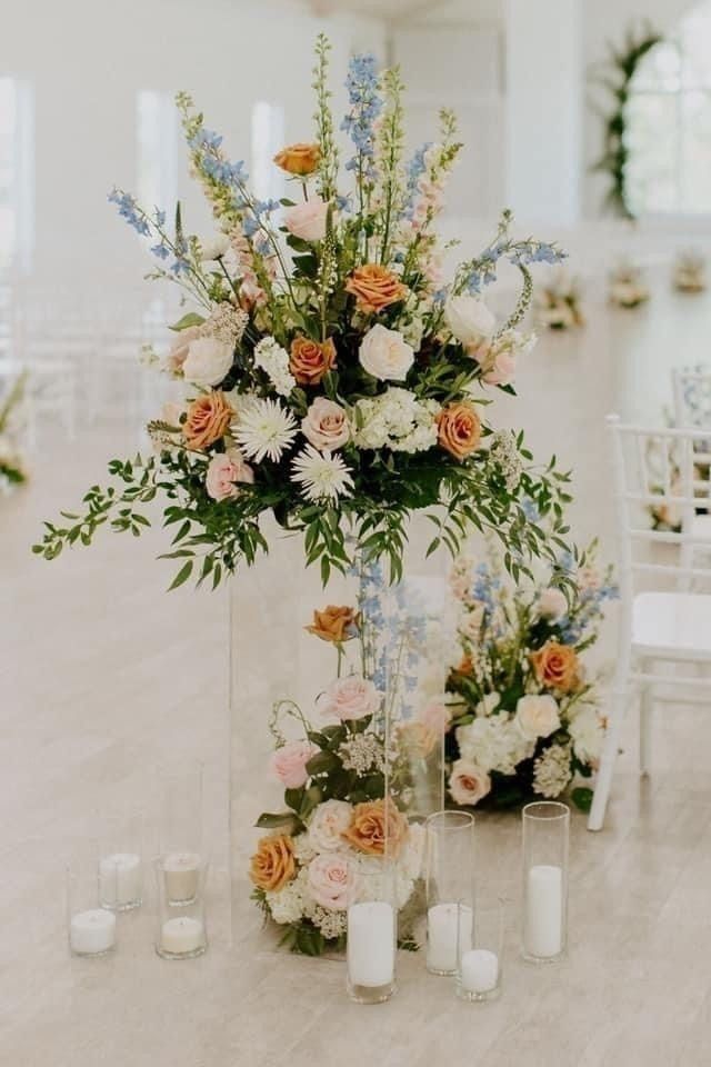 Tall pastel floral cross centerpiece with candles in a bright white room