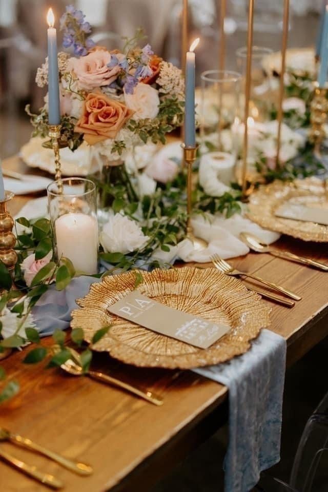 Elegant dining table with gold accents, candles, flowers, and woven chargers set for a formal event