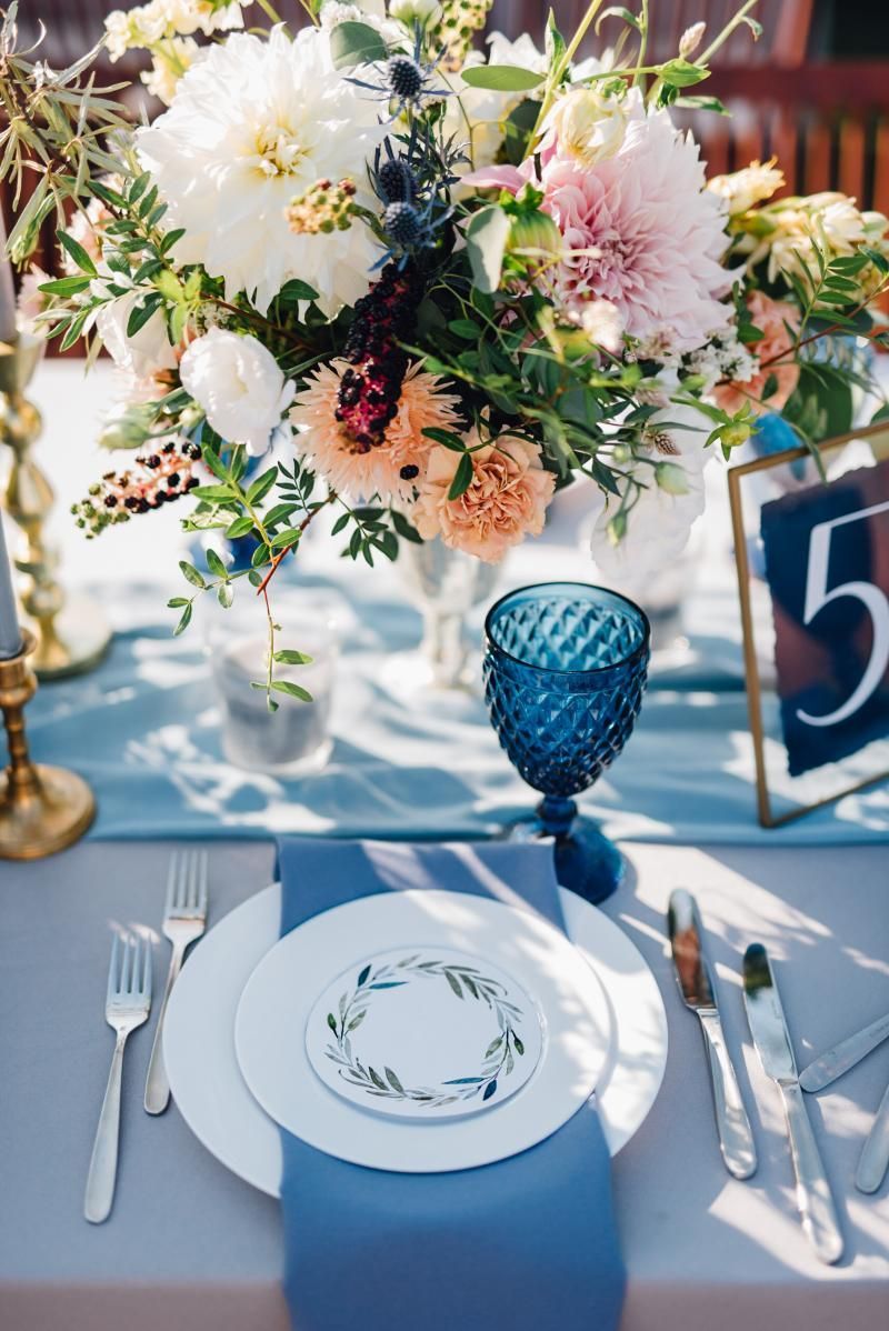 Elegant table setting with blue and white place settings, floral centerpiece, and table number 5
