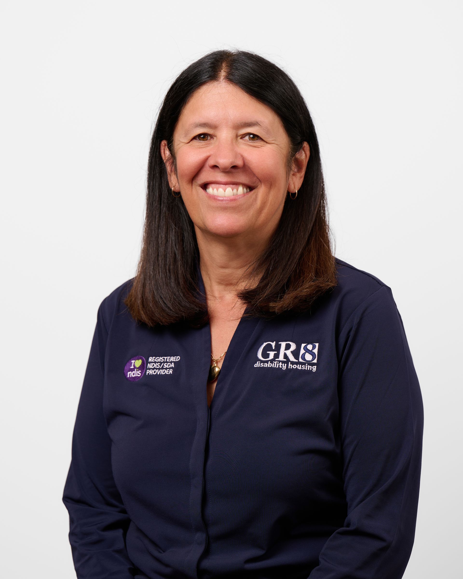 A woman wearing a blue shirt with the word gre on it is smiling.