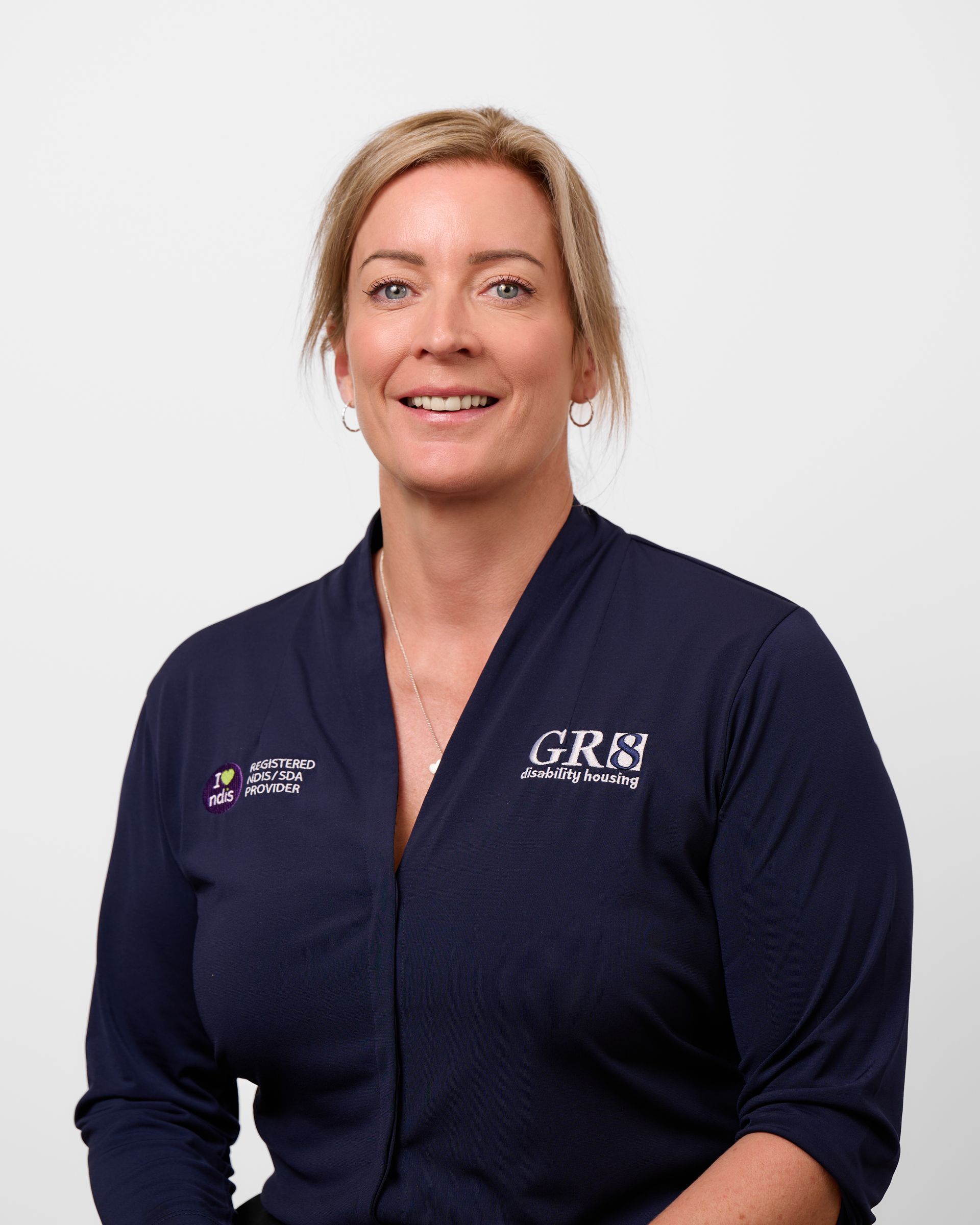 A woman is wearing a blue polo shirt and smiling.