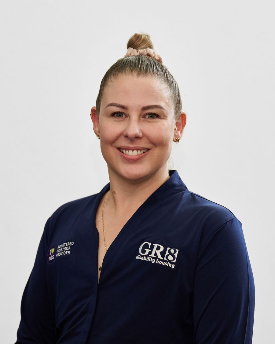 A man with a mustache is wearing a white shirt and smiling.