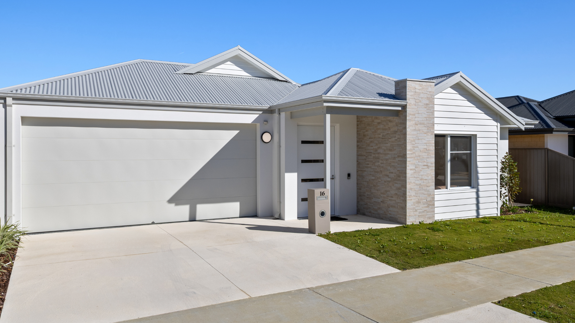 Gray and white suburban home with garage and driveway on a sunny day.