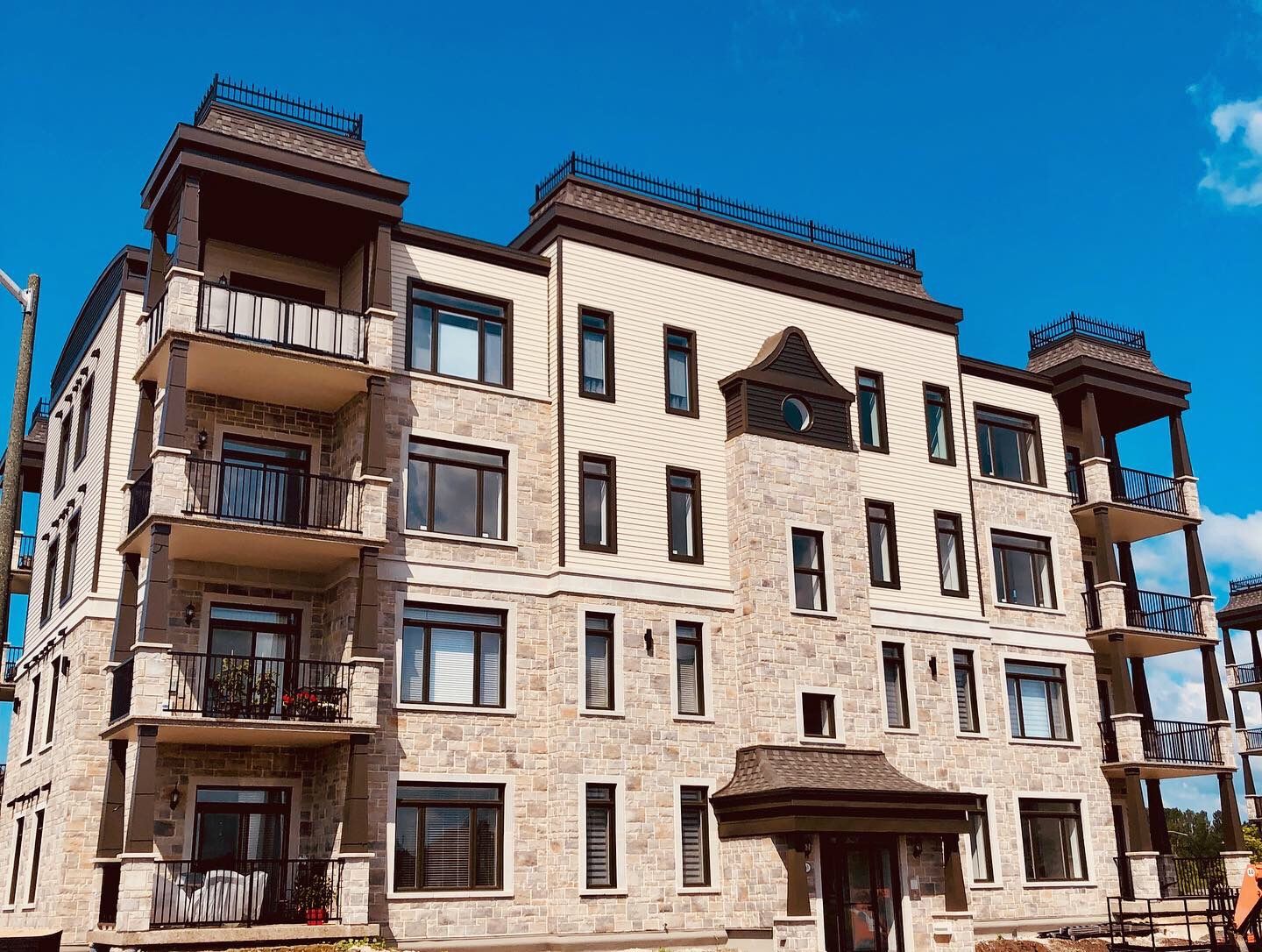 Immeuble de plusieurs étages en pierre beige avec balcons, touches de brun et ciel bleu.