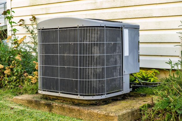 An air conditioner is sitting on the side of a house.