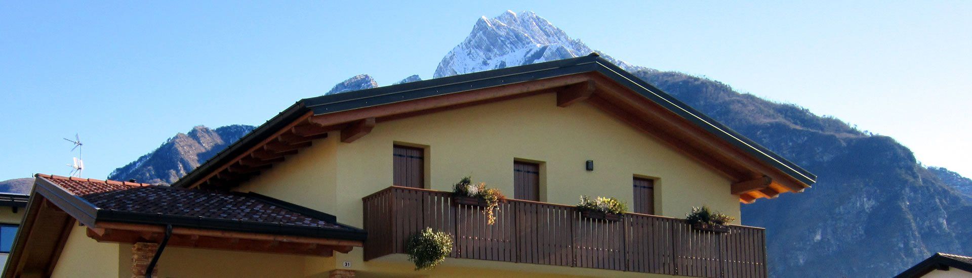 Un edificio a due piani con un balcone di fronte a una montagna.