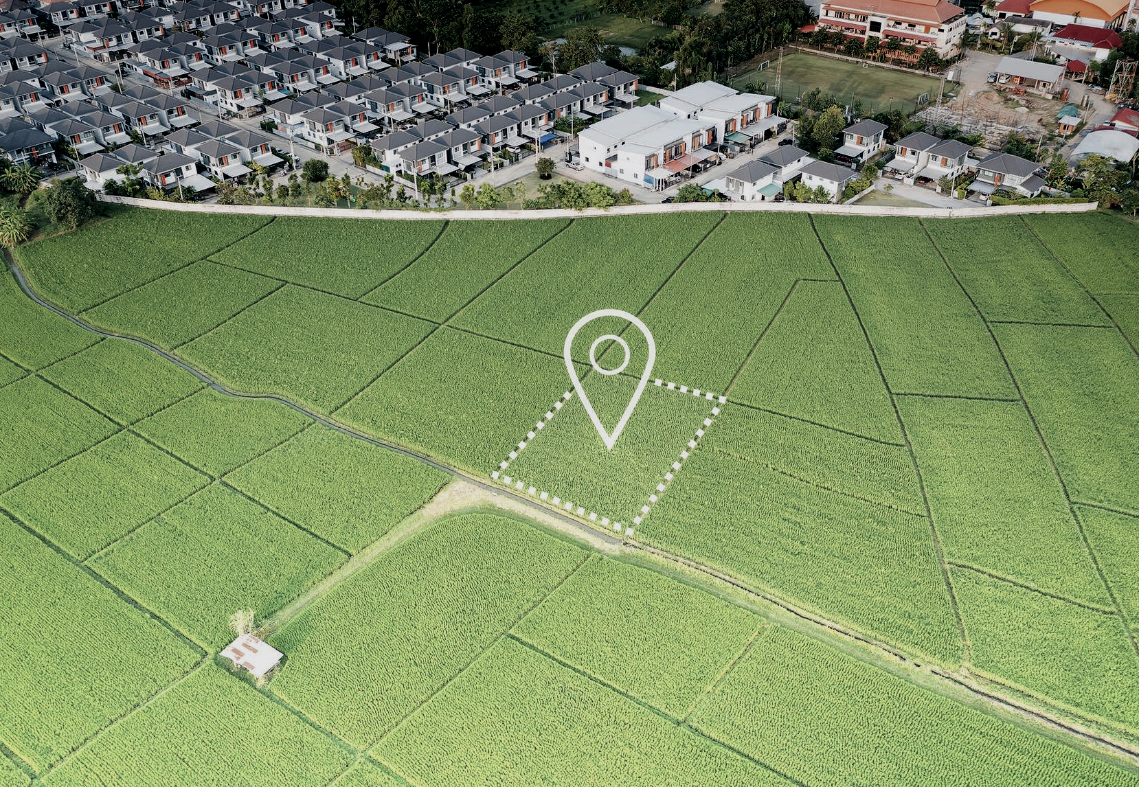 Vista aerea di un campo verde con un segnaposto e un alloggio sullo sfondo.