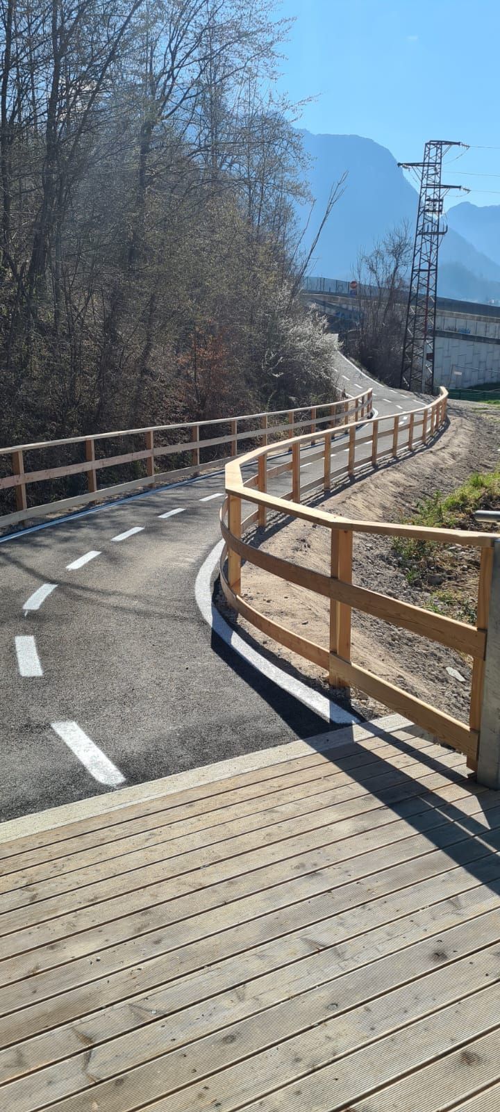 Un sentiero tortuoso con ringhiere in legno e una terrazza in legno in un ambiente naturale.