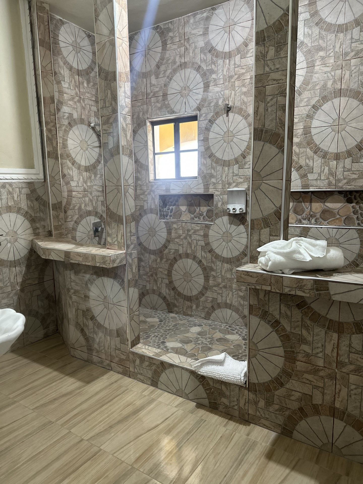 A bathroom with a walk in shower , sink , toilet and mirror.