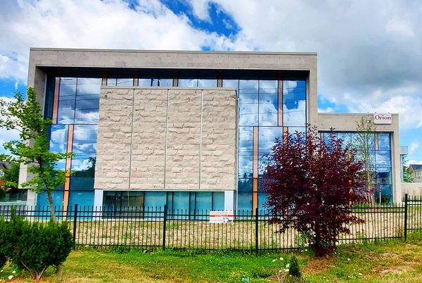 A large building with a lot of windows is behind a fence.