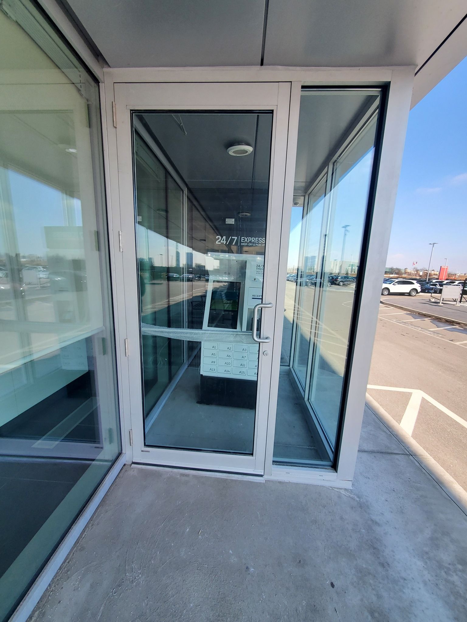 A white door with a lot of glass is open to a parking lot.