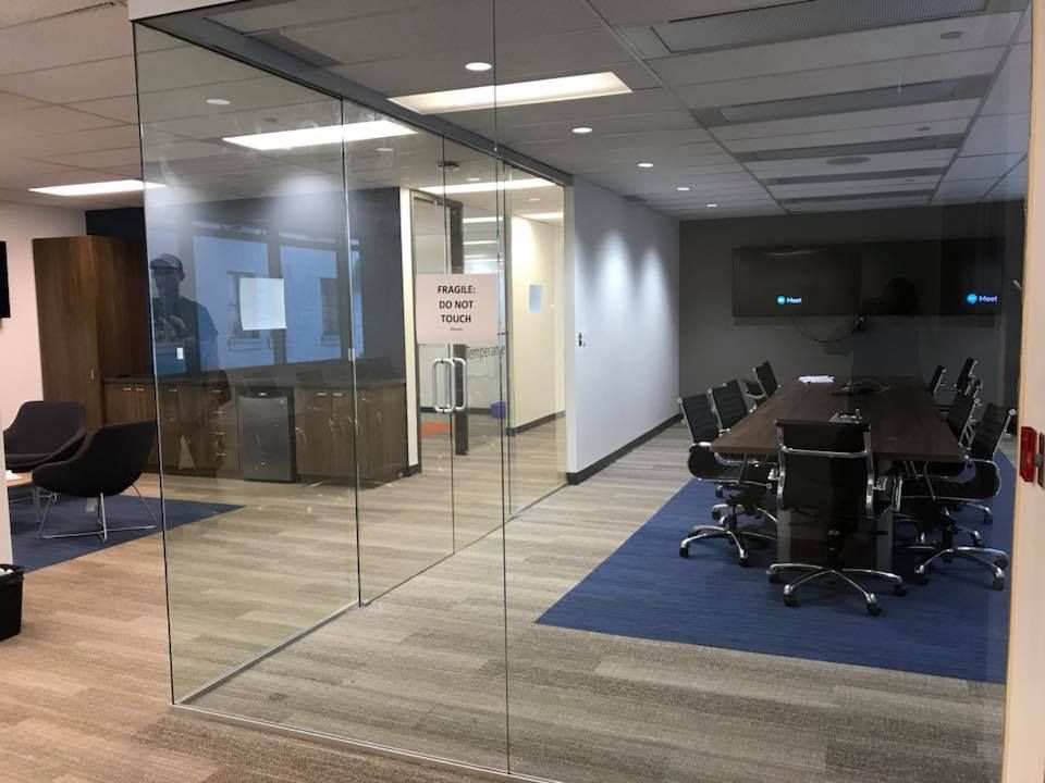 A conference room with a glass wall and a table and chairs.