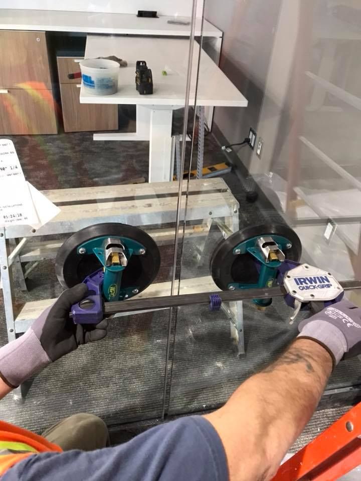 A man is using a vacuum lifter to lift a piece of glass.