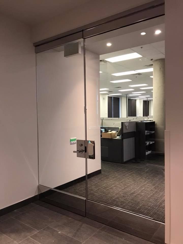 A glass door in an office with a cubicle in the background.