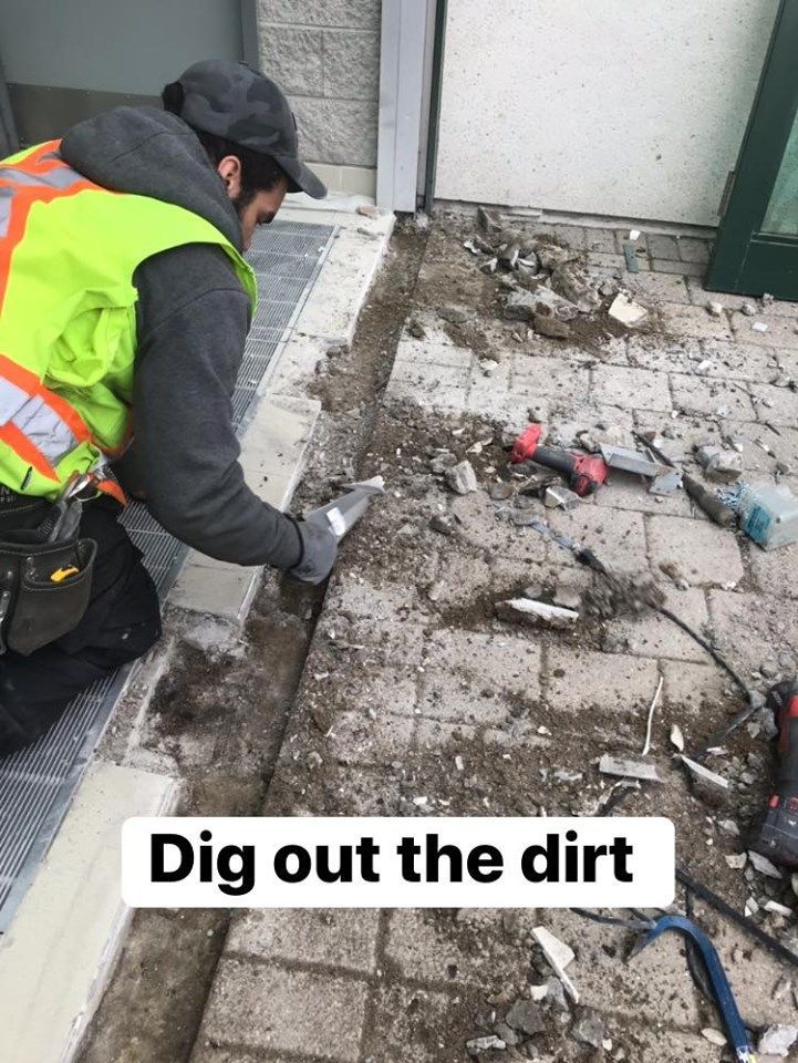 A man is digging out the dirt on a sidewalk.