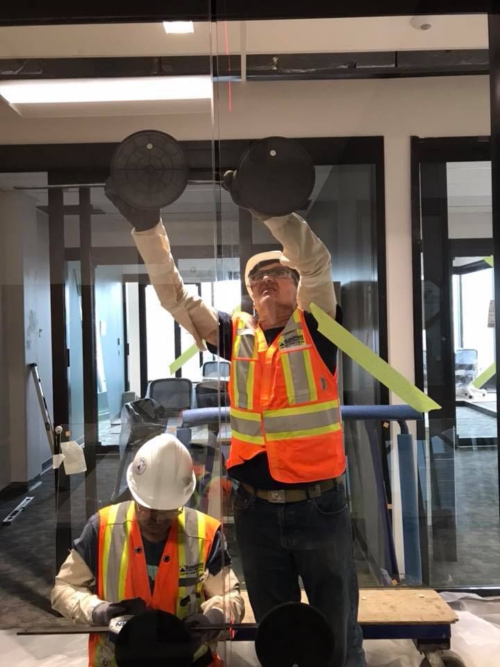 Two construction workers are working on a glass wall.