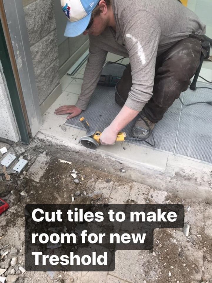 A man is cutting tiles to make room for a new threshold.