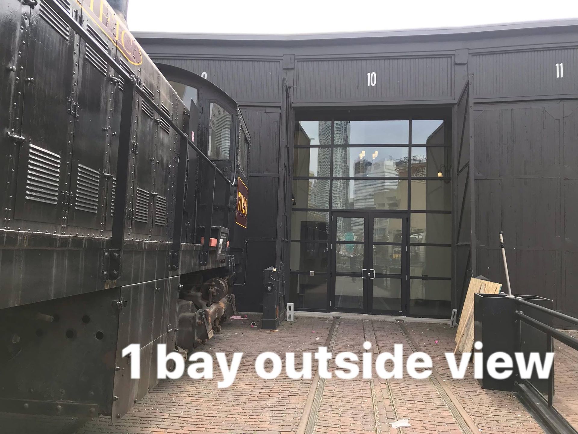 A train is parked in front of a building that says 1 bay outside view