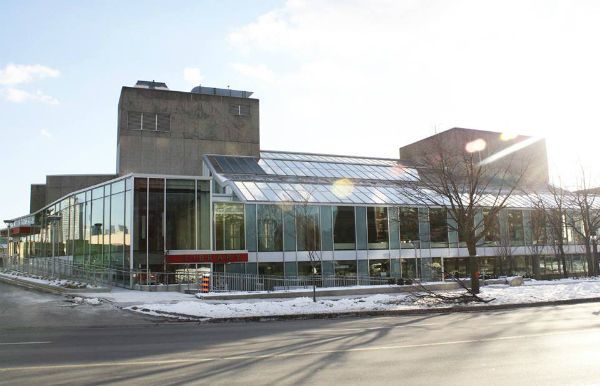 A large building with a lot of windows is surrounded by snow and trees.