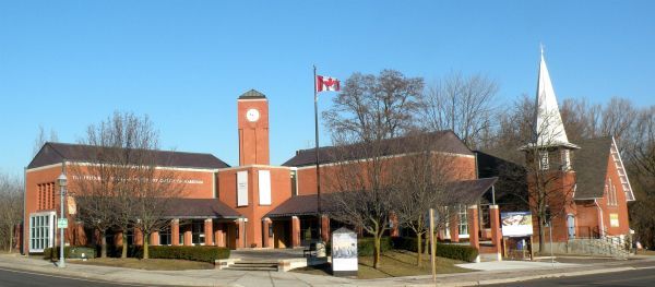 A large brick building with a clock tower and a canadian flag