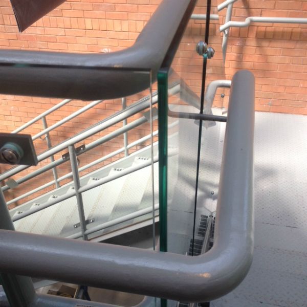 A staircase with a glass railing and a brick wall behind it