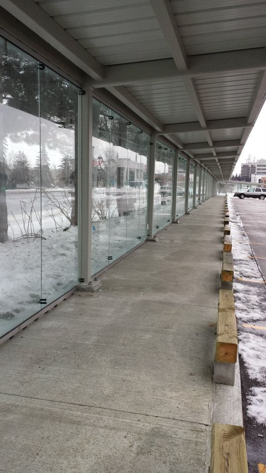 A covered walkway with a lot of windows and snow on the ground.