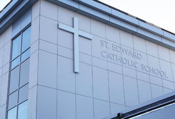 A cross is on the side of a building that says st. edward catholic school