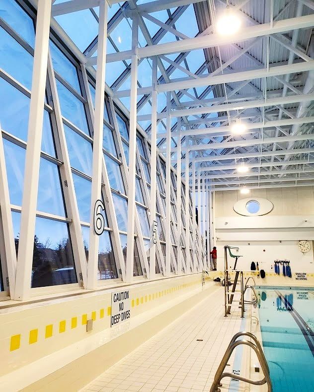 A large indoor swimming pool with a caution sign on the wall