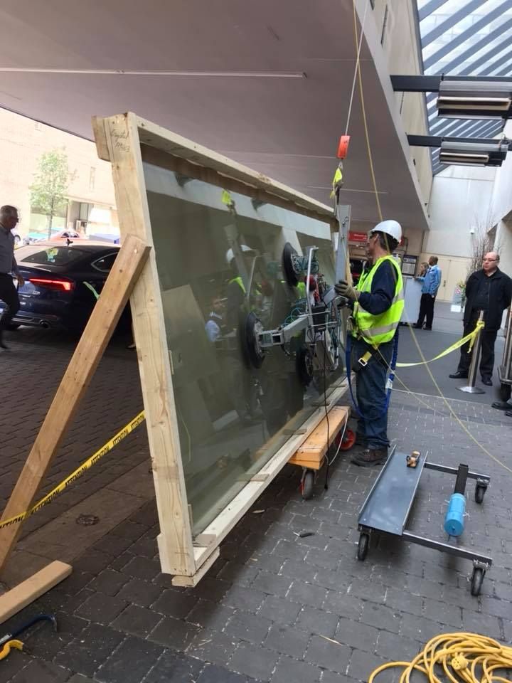 A large piece of glass is being lifted by a vacuum lifter.