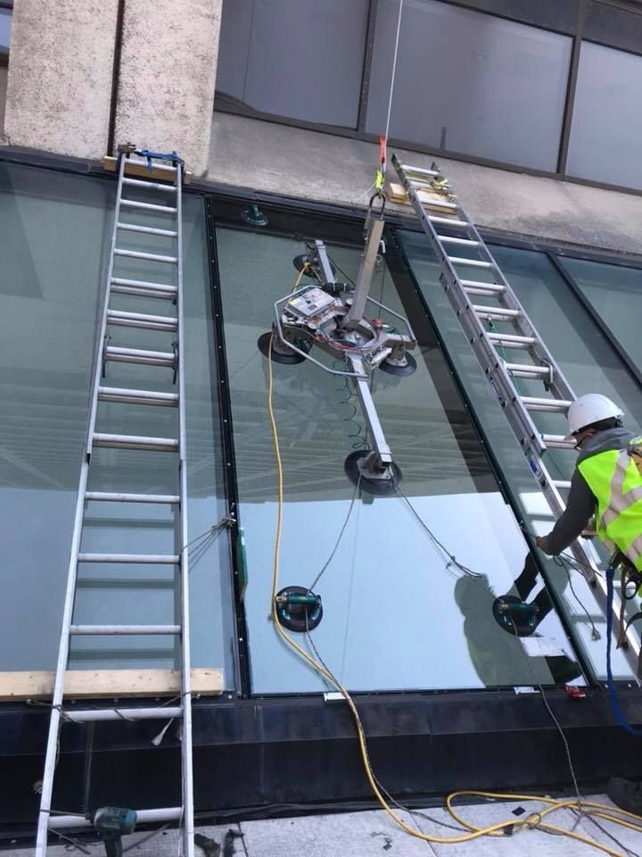 A man is working on a glass roof with a vacuum lifter.