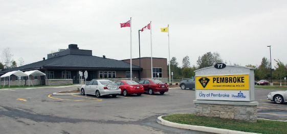 A parking lot with cars parked in front of a pembroke building.