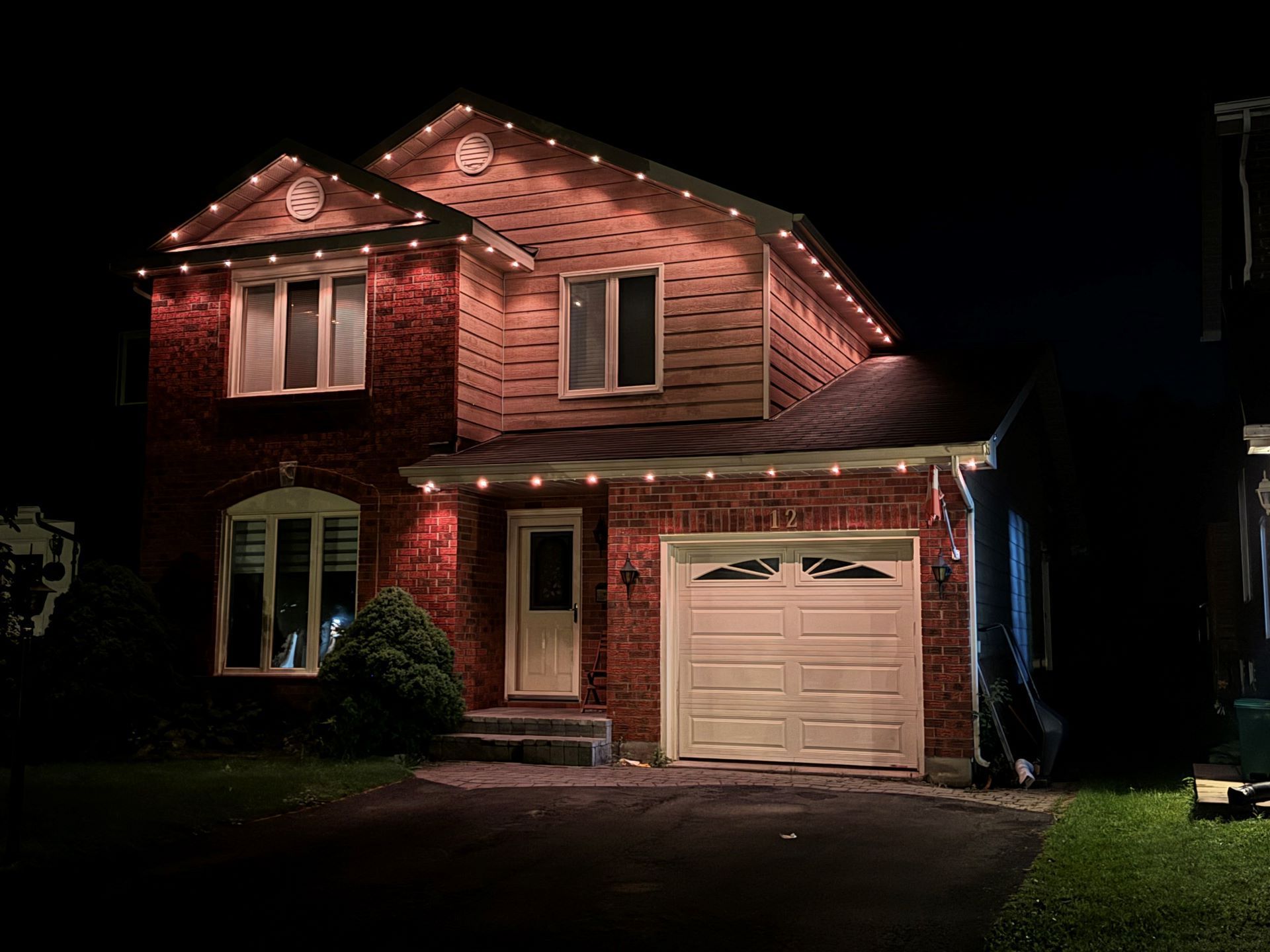 A house with christmas lights on it is lit up at night.