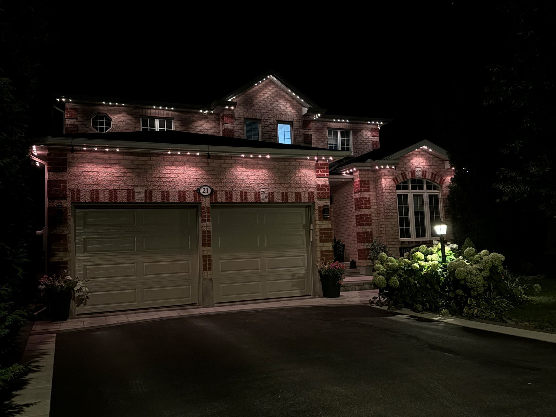 A large brick house is lit up at night with christmas lights