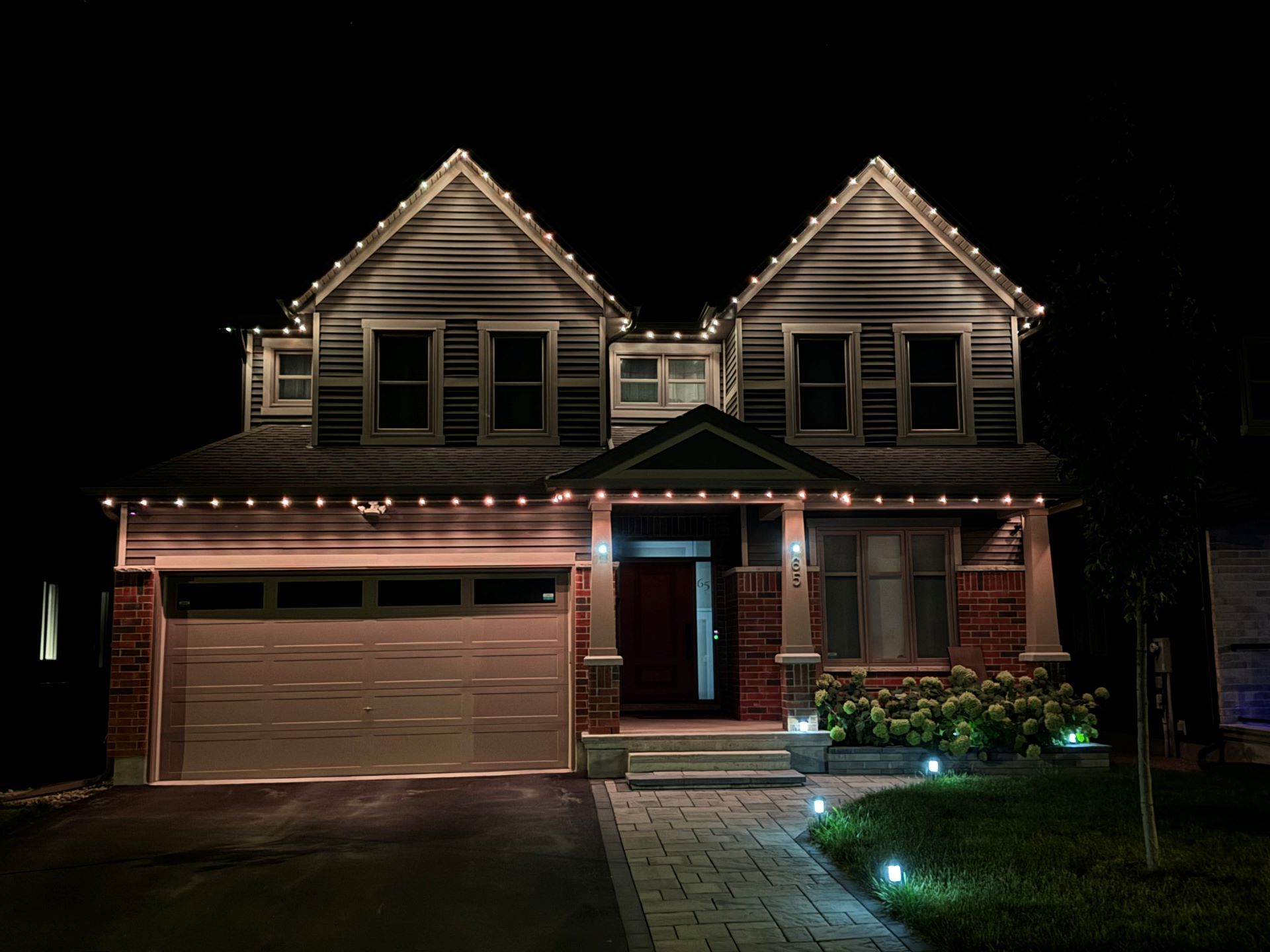A house with christmas lights on it is lit up at night.