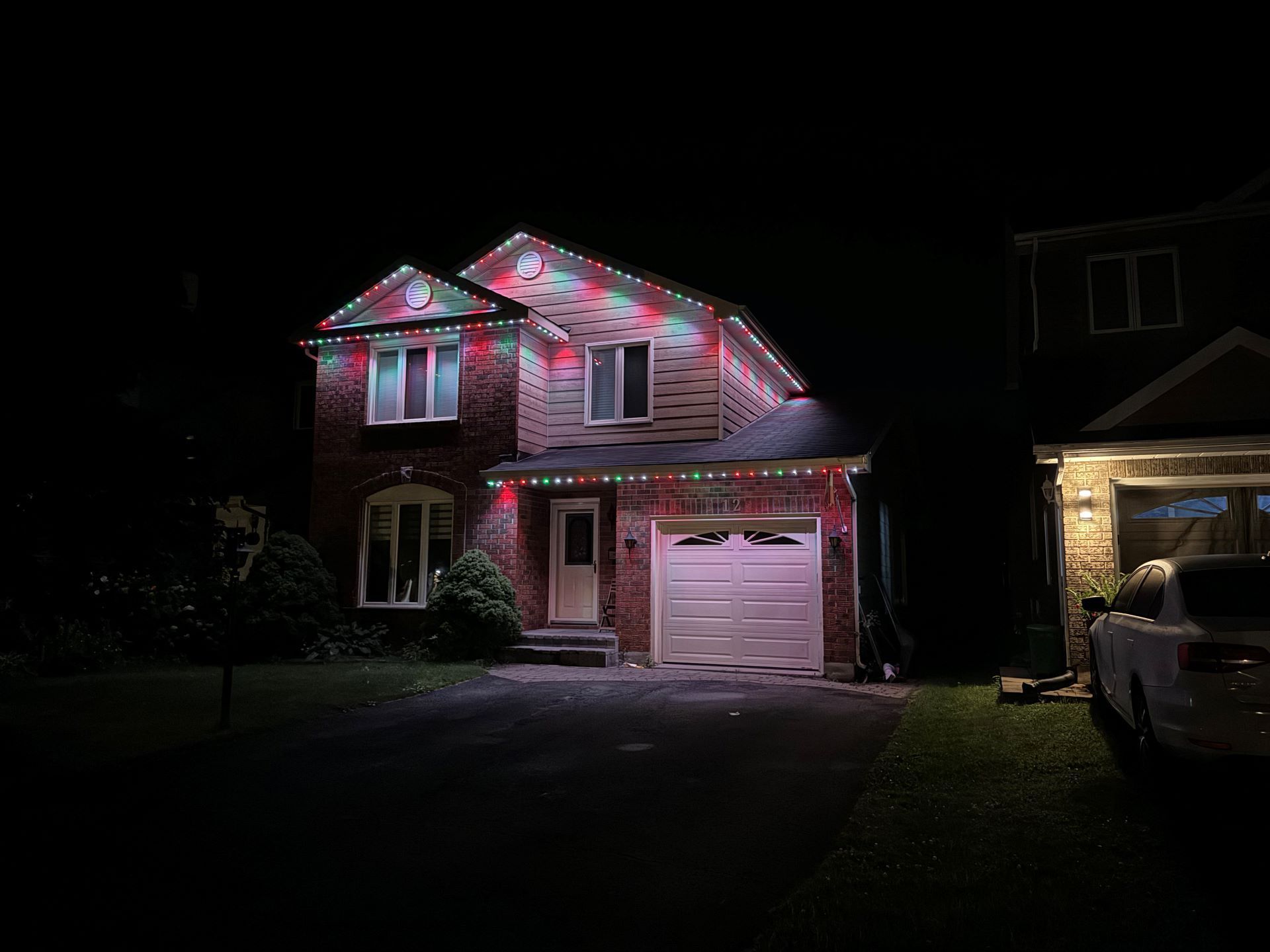 A house with christmas lights on it is lit up at night.